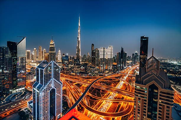 Dubai skyline at night, the Sheikh Zayed Road interchange lit with traffic